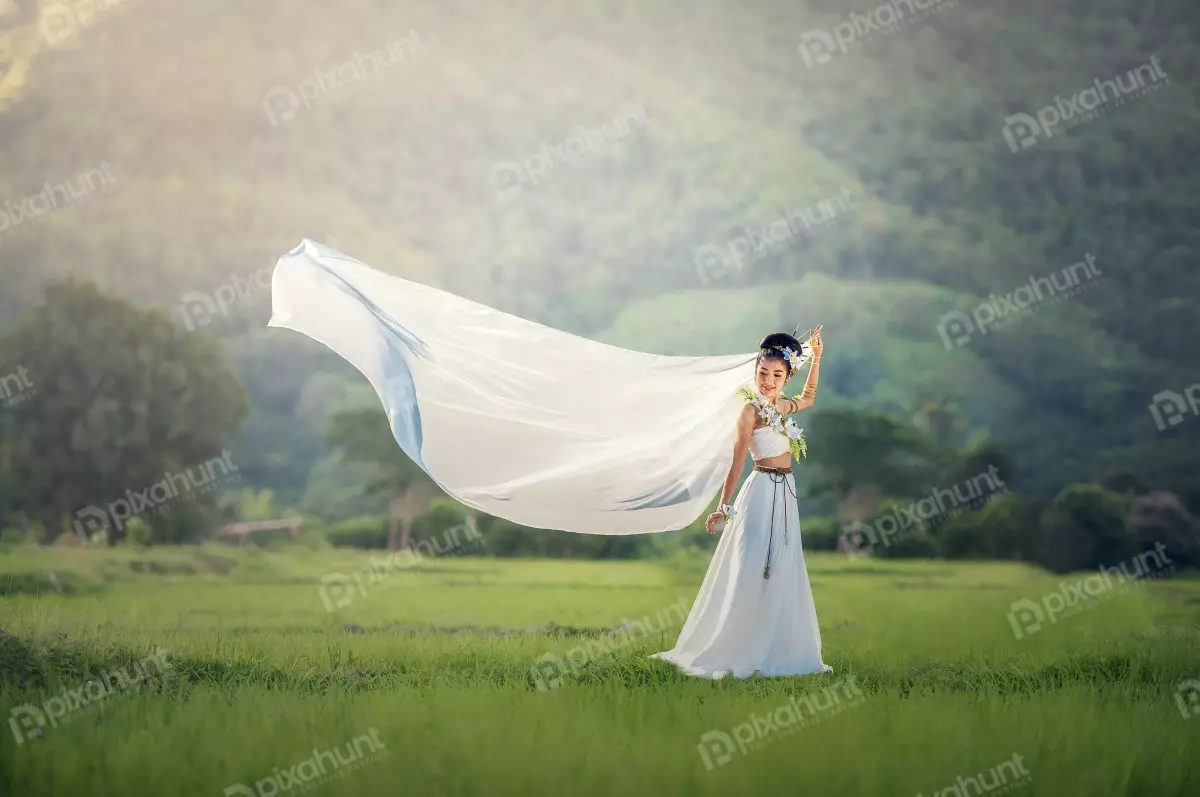 Free Premium Stock Photos A beautiful young girl wearing a white dress and standing in a field of tall grass and the wind is blowing her hair and dress