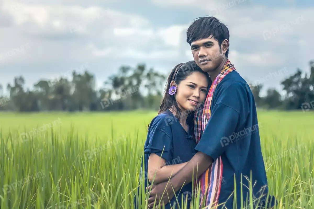 Free Premium Stock Photos A couple standing in a green field and man is wearing a blue shirt and the woman is wearing a traditional Thai dress