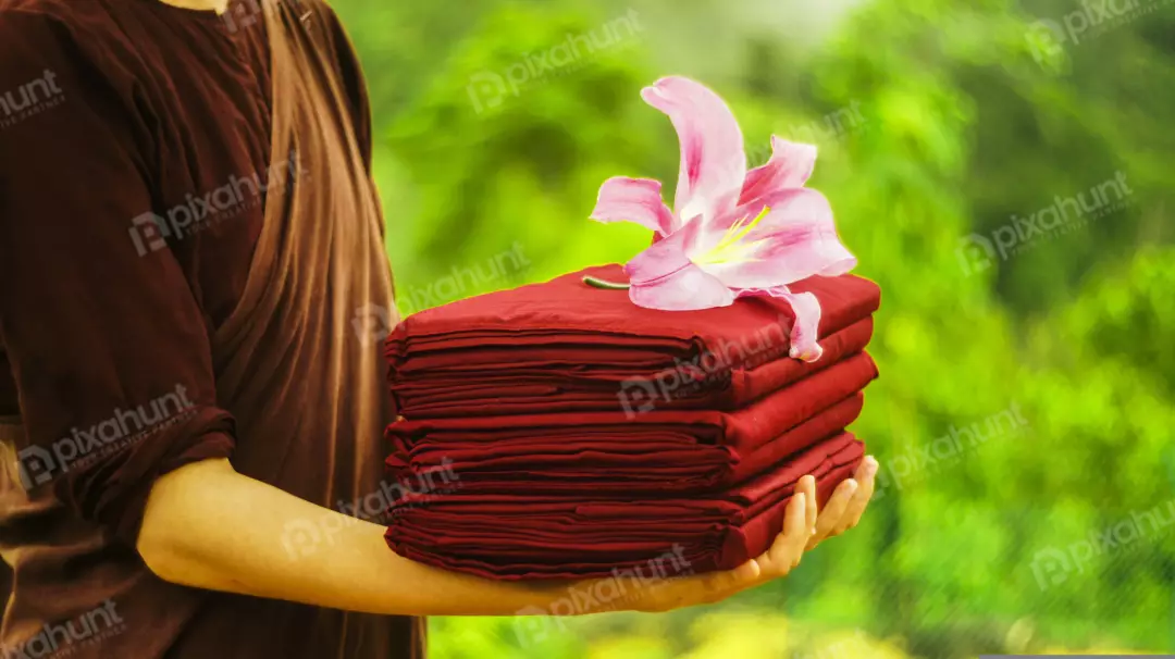 Free Premium Stock Photos A Monk holding a stack of red cloths With flower