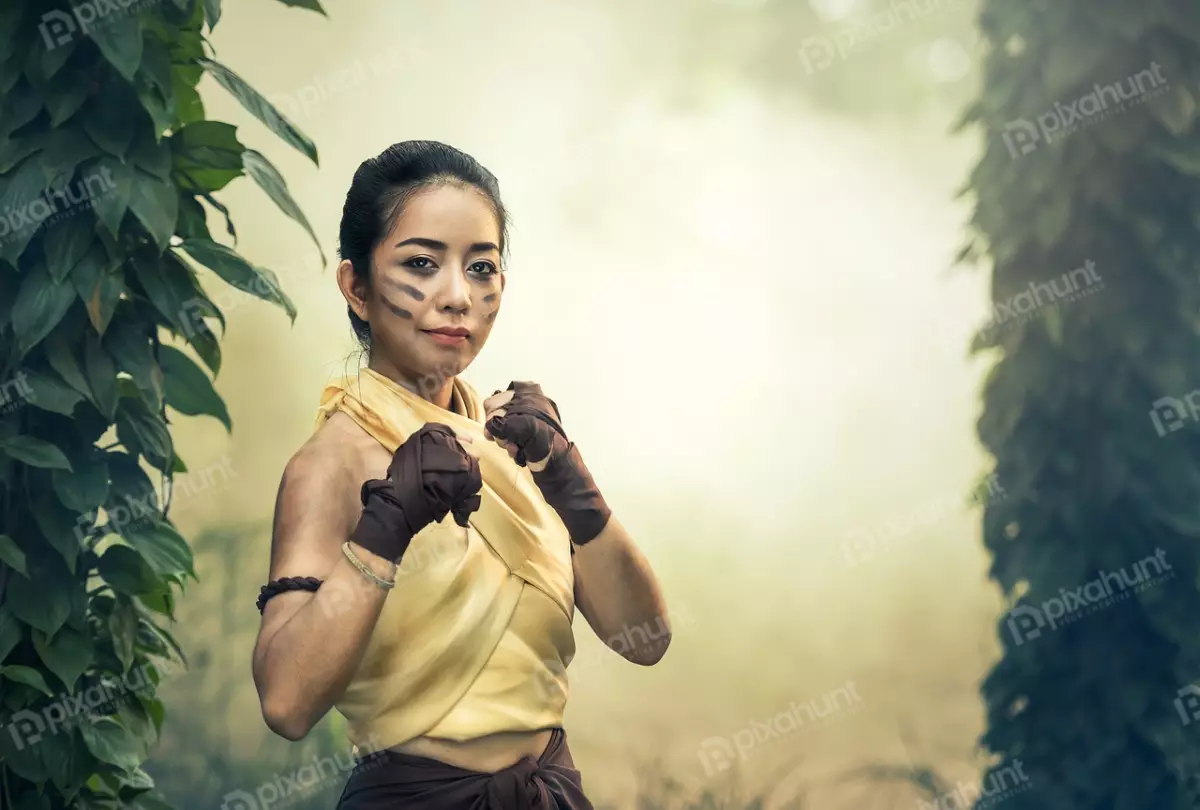 Free Premium Stock Photos A woman in a fighting stance and wearing a yellow tank top and brown shorts, and her hair is tied back in a bun
