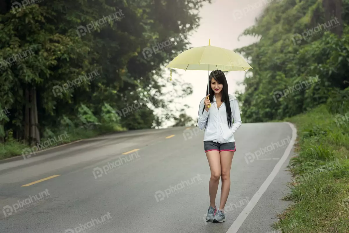 Free Premium Stock Photos A woman standing on a road and wearing a white shirt, gray shorts, and sneakers also lady holding a yellow umbrella