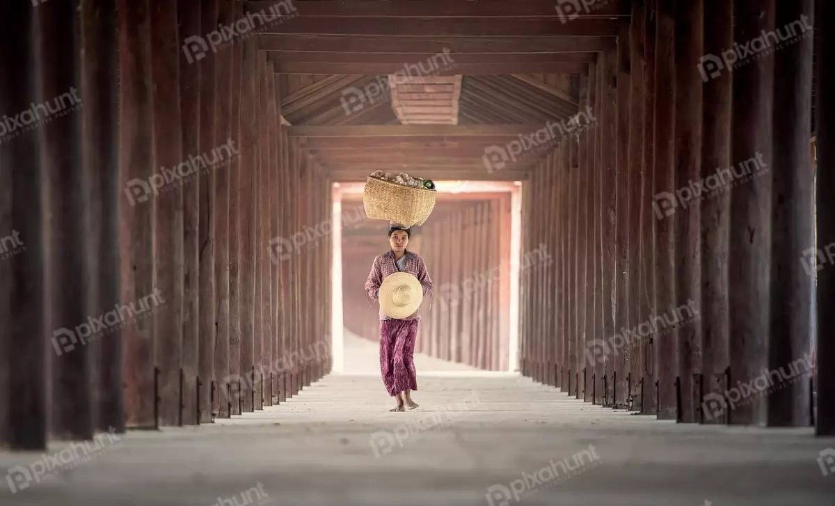 Free Premium Stock Photos A woman who is walking away from the camera and carrying a large basket on her head and is wearing a traditional Burmese longyi