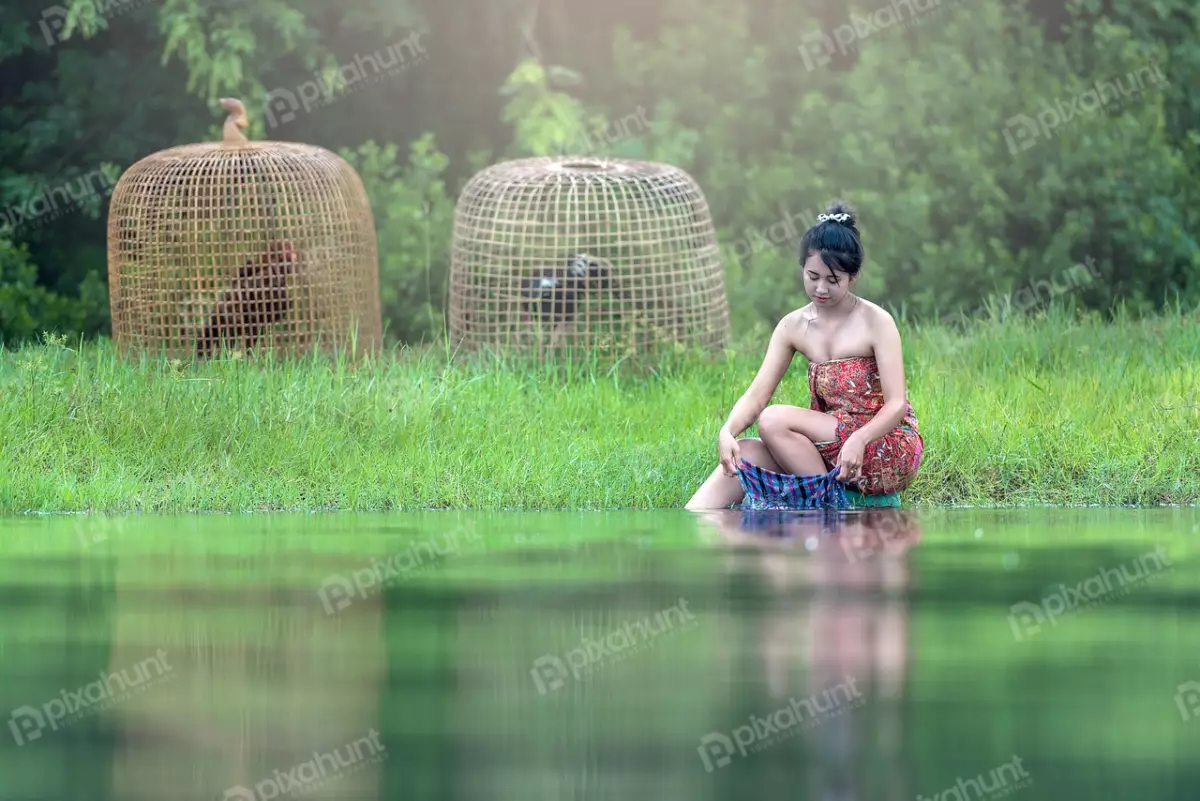 Free Premium Stock Photos A young girl in a traditional Thai outfit sitting on the edge of a river and washing clothes in the water