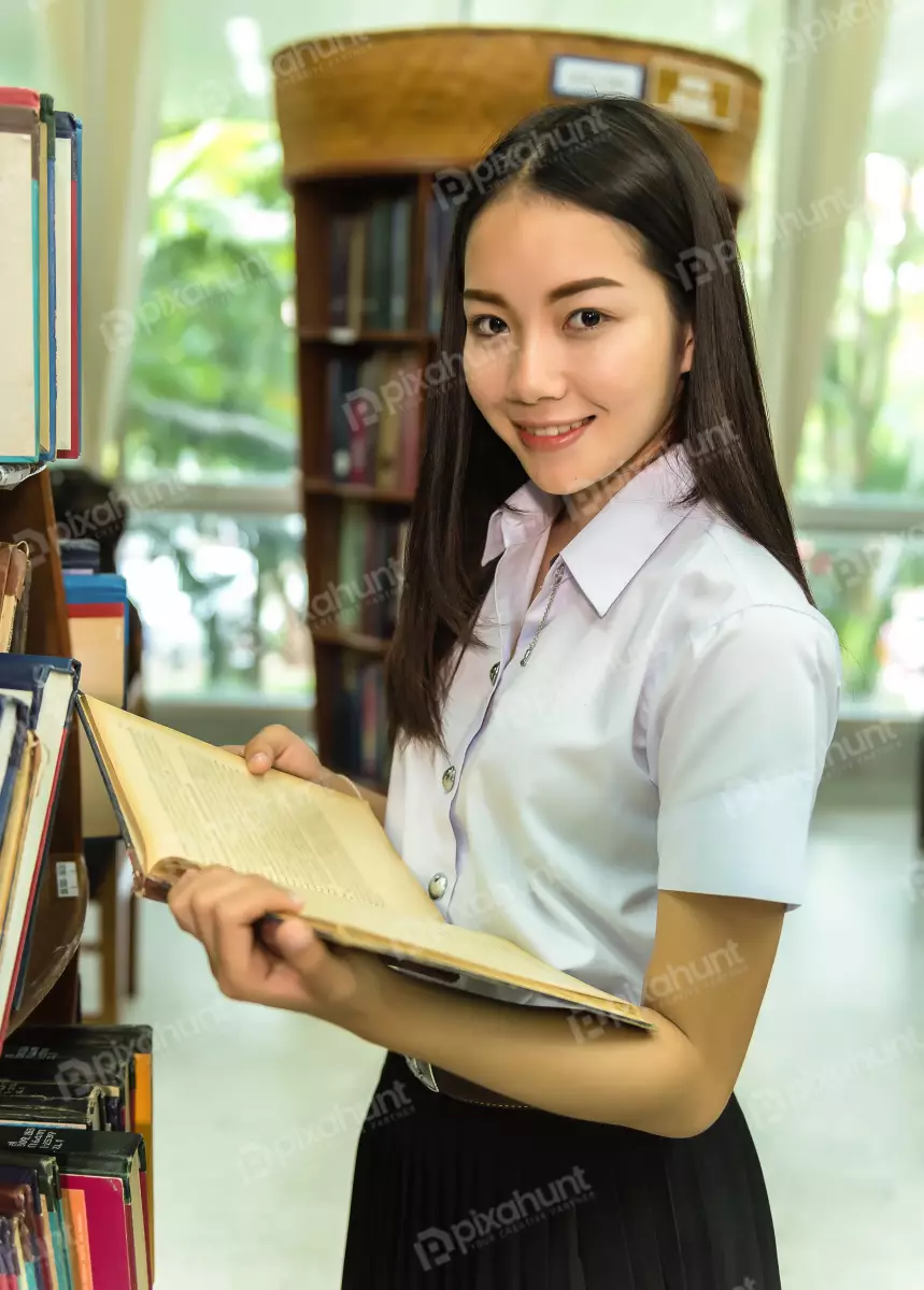 Free Premium Stock Photos A young woman standing in a library, looking at the camera with a slight smile