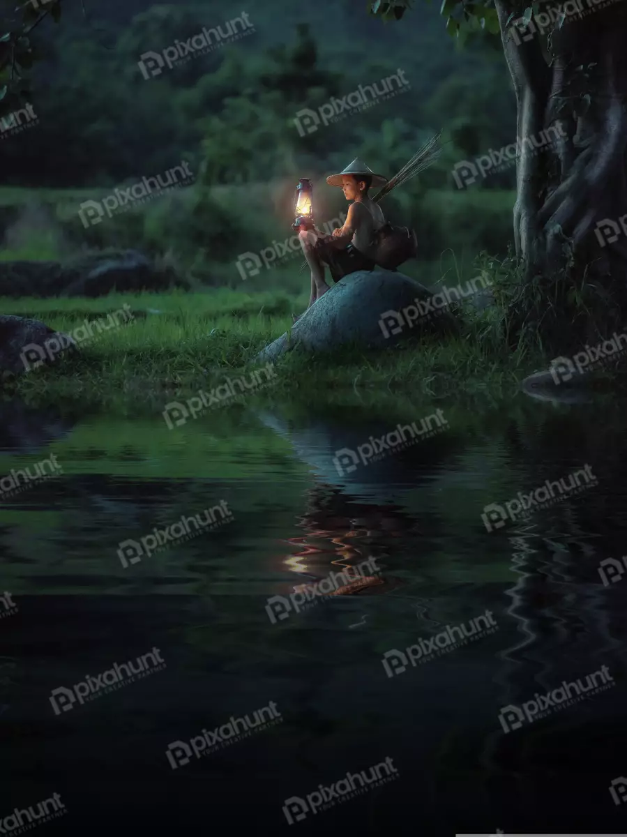 Free Premium Stock Photos Boy sitting on a rock in the middle of a river and wearing a traditional Vietnamese hat with holding a lantern in his right hand