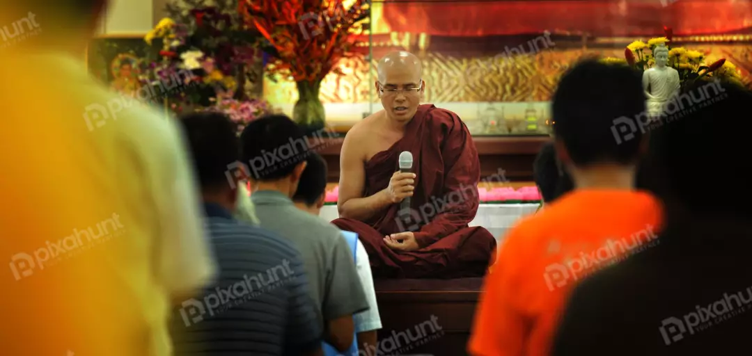 Free Premium Stock Photos Buddhist monk sitting on a raised platform, with a microphone in his hand