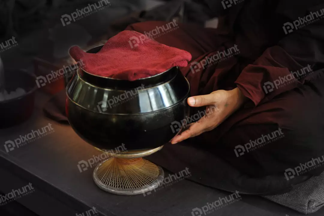 Free Premium Stock Photos Contains a monk sitting on a cushion with a black alms bowl in front of him
