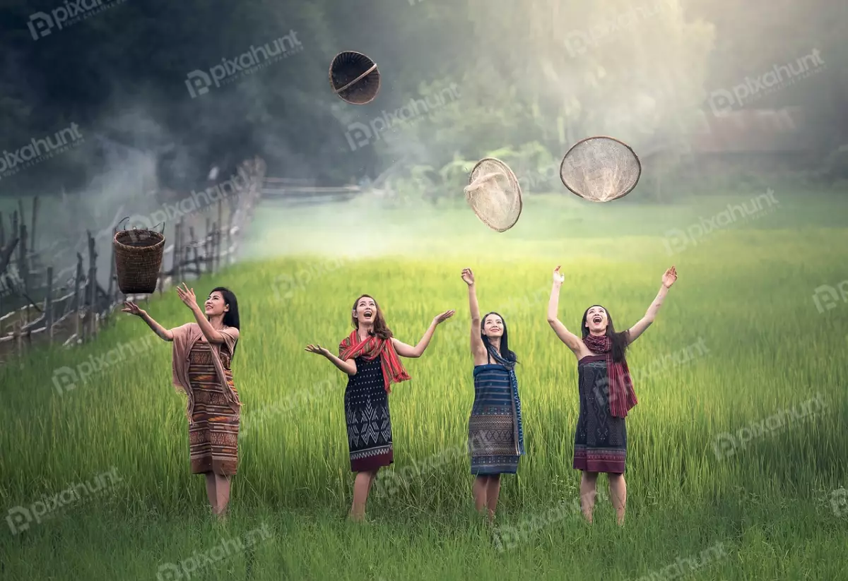 Free Premium Stock Photos Four beautiful women in traditional Hmong clothing and standing in a lush green rice field, and each woman is holding a different farming tool