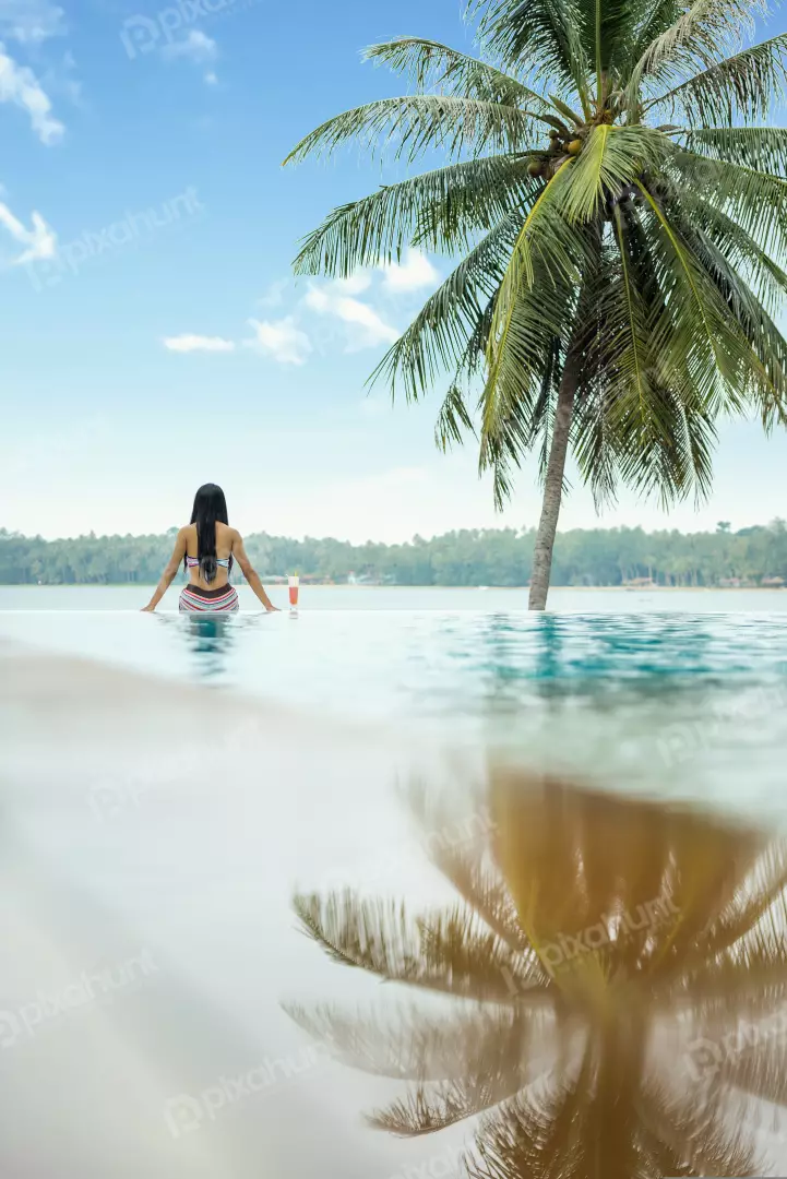 Free Premium Stock Photos Girl is facing away from the camera, looking out at the view And woman in a striped bikini sitting on the edge of an infinity pool