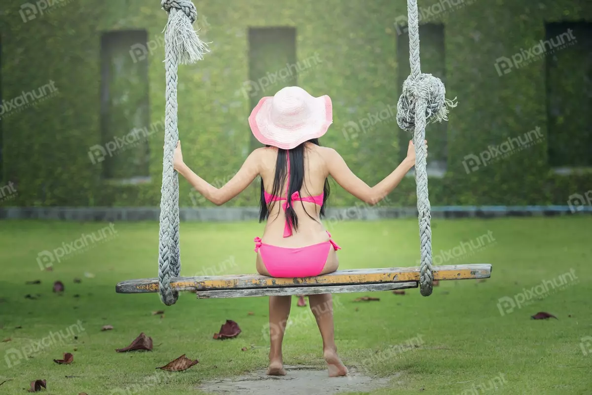 Free Premium Stock Photos Girl is wearing a wide-brimmed hat that shades her face from the sun And  sitting on a wooden swing, which is suspended from two thick ropes