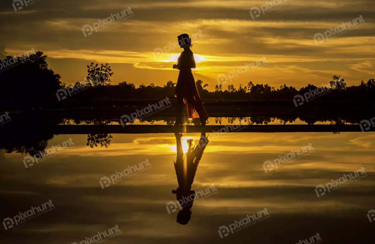 Free Premium Stock Photos Girl walking on a beach at sunset sky is a bright orange, and the water is calm
