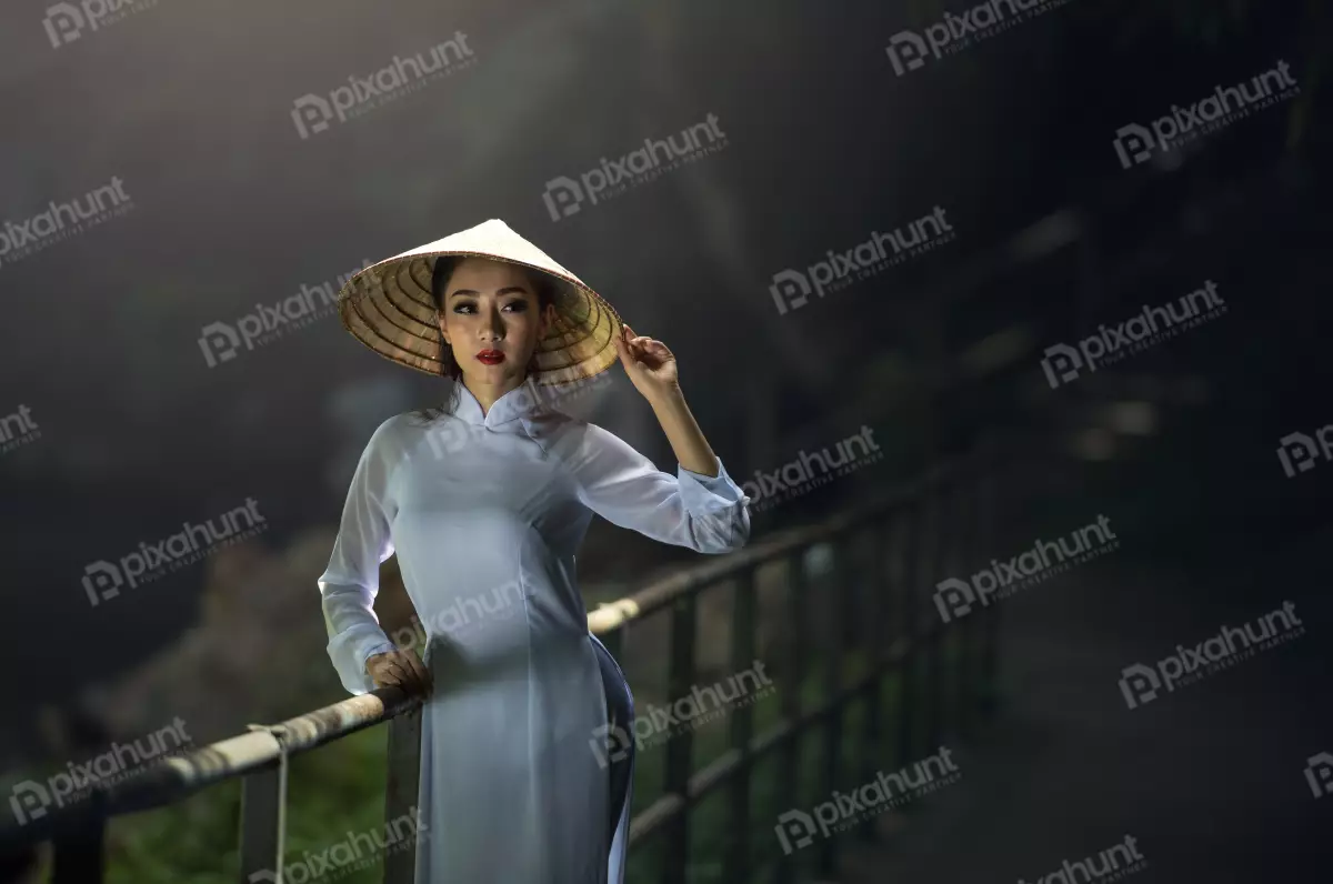 Free Premium Stock Photos Girl wearing a traditional Vietnamese conical hat with standing in a dark place with the light from a window falling on her face