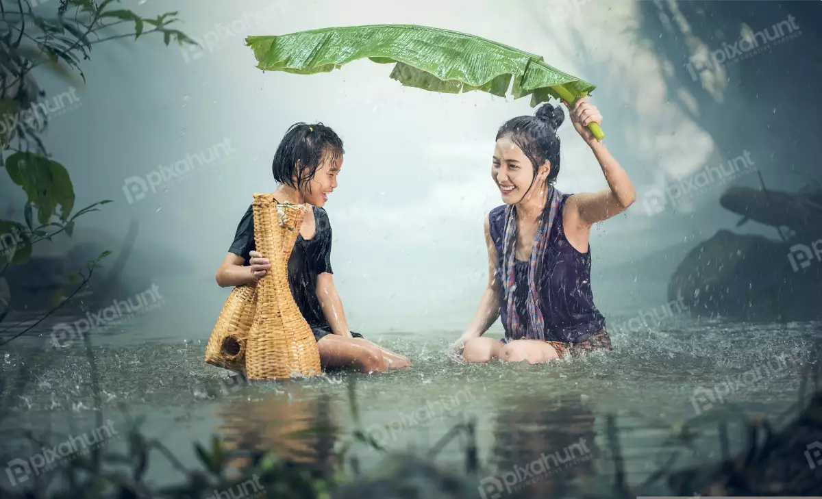 Free Premium Stock Photos Mother and her child is holding a banana leaf over her head to protect them from the rain