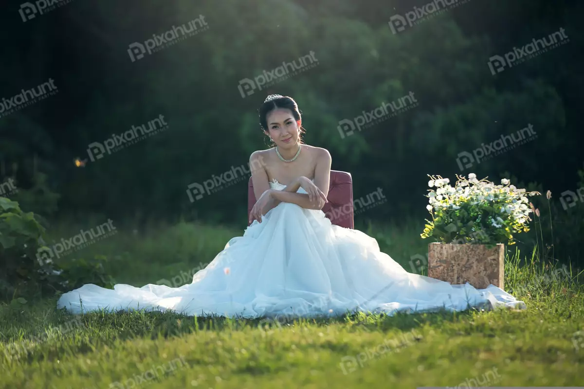Free Premium Stock Photos The bride is sitting on a red chair in the middle of a field and wearing a white wedding dress and has her hair in a bun