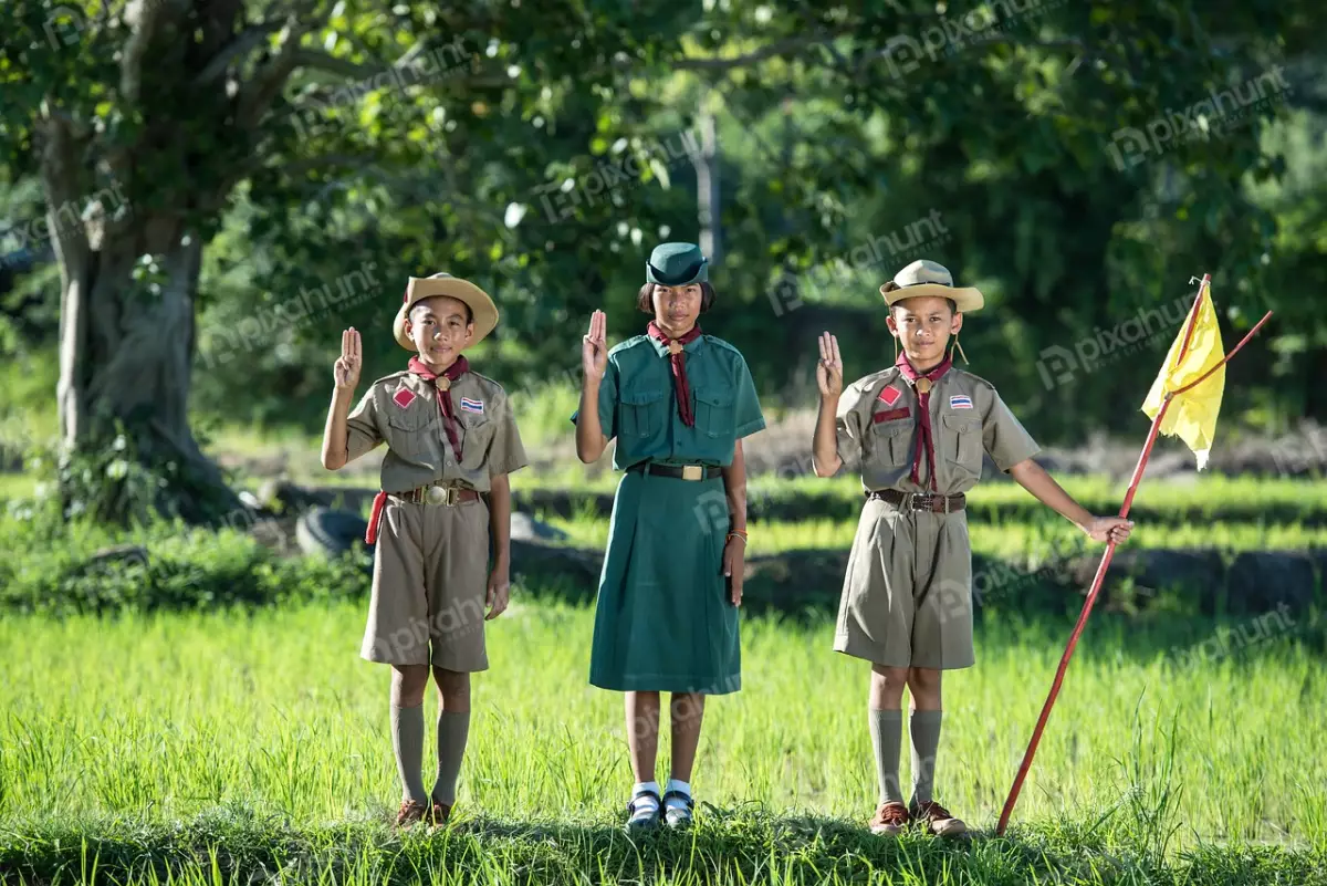Free Premium Stock Photos Three scouts standing in a field, with the tallest in the middle and wearing green shirts and brown shorts