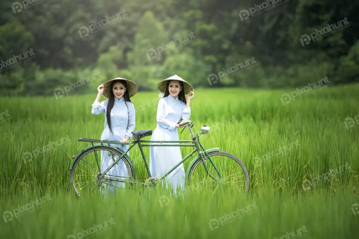 Free Premium Stock Photos Two beautiful young women in traditional Vietnamese clothing standing in a lush green rice field And Also wearing conical hats and white dresses