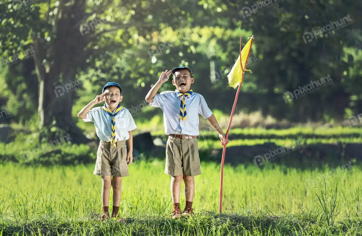 Free Premium Stock Photos Two boy scouts standing in a field saluting and holding a flag and both wearing scout uniforms and looking off to the left