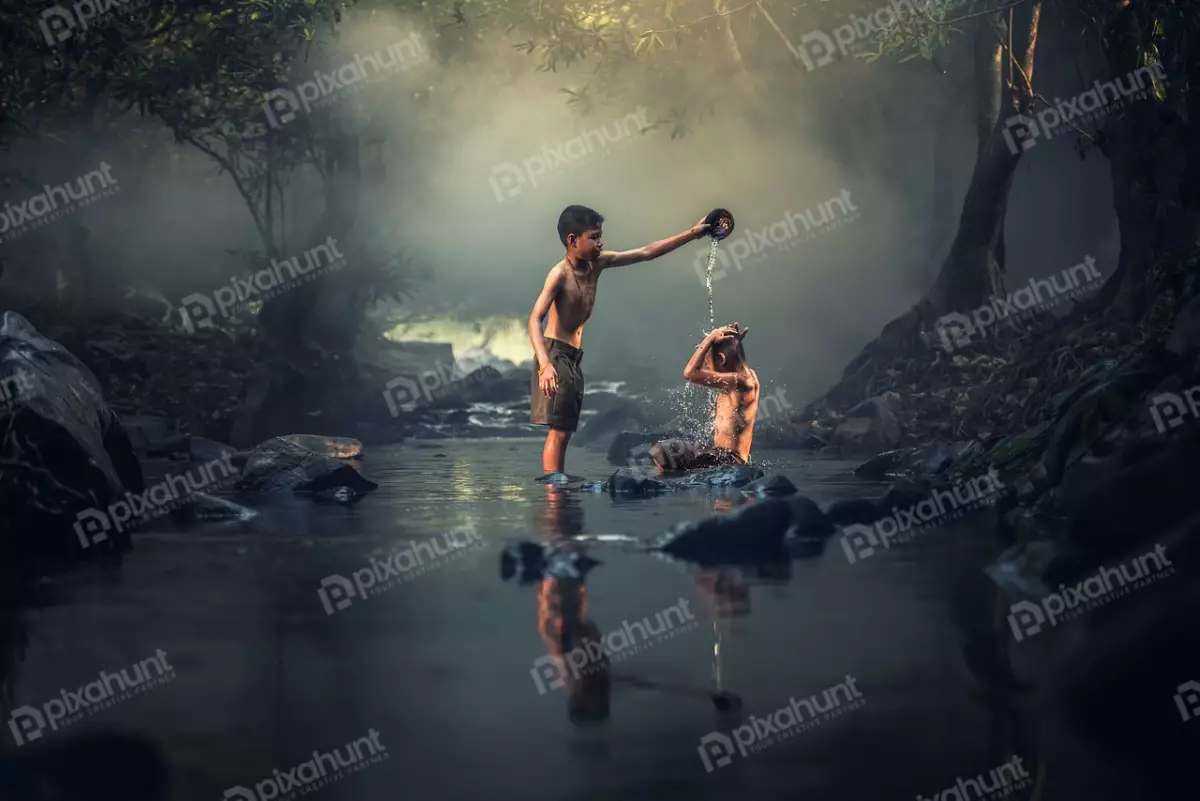 Free Premium Stock Photos Two boys who are bathing in a river and standing in the water and the one on the left is pouring water over the head of the boy on the right
