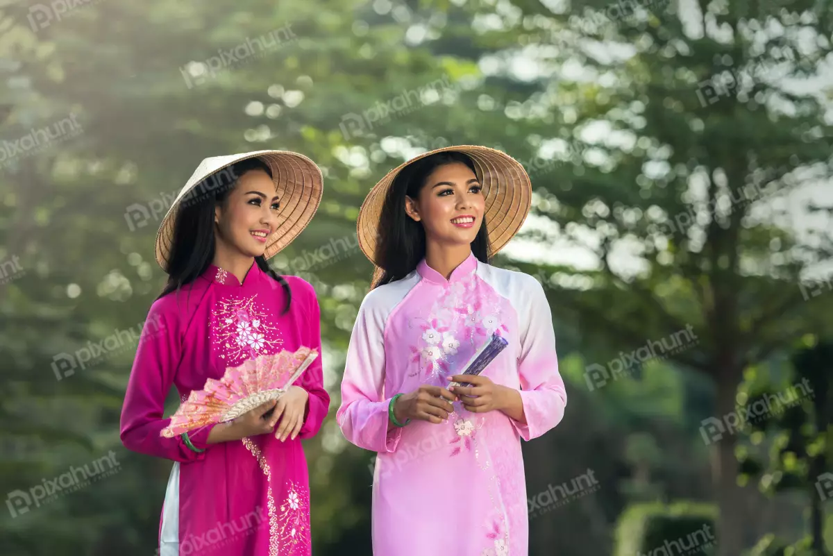 Free Premium Stock Photos Two Vietnamese women wearing traditional ao dai dresses and both smiling and holding fans