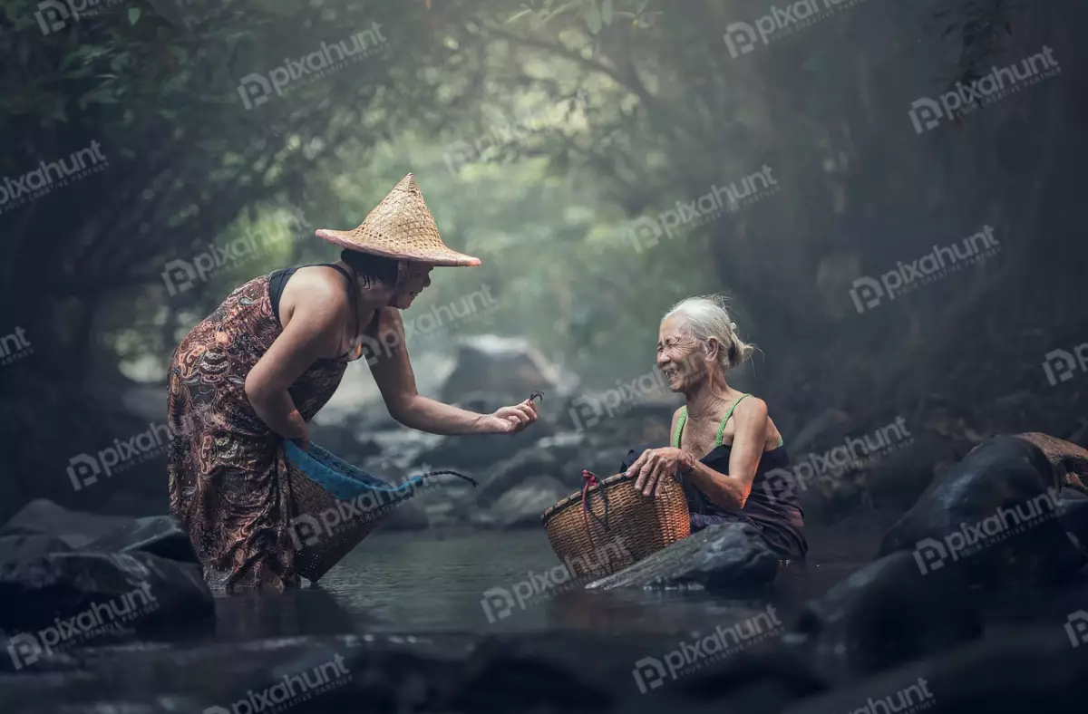Free Premium Stock Photos Two women standing in a river and both wearing traditional clothing and are carrying baskets