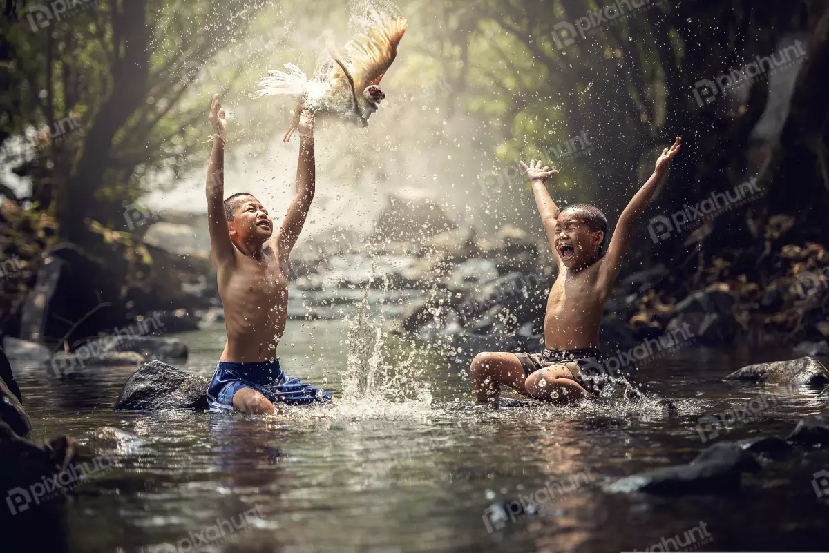 Free Premium Stock Photos Two young boys playing in a river and boys are both sitting on rocks in the river also they are both holding a chicken
