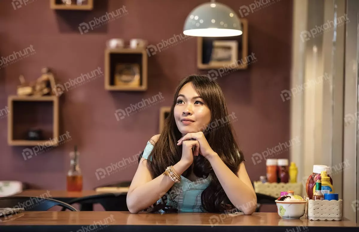 Free Premium Stock Photos Woman sitting at a table in a restaurant and She is looking off to the side and smiling also thinking sonthing