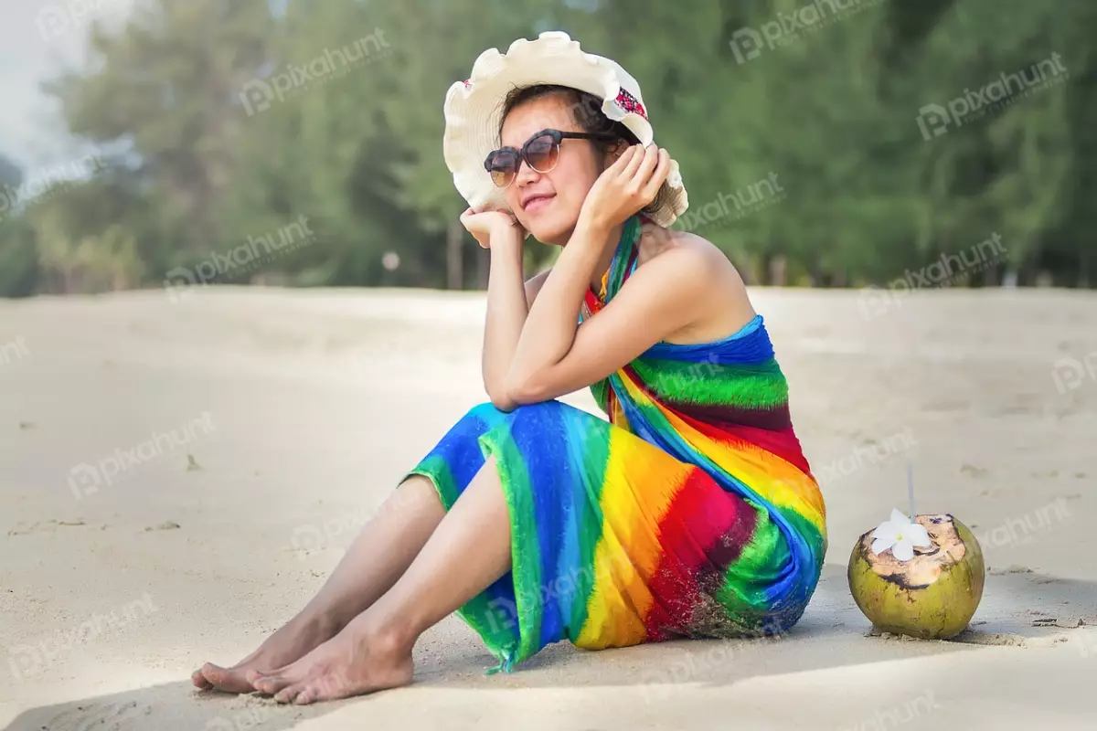 Free Premium Stock Photos Woman sitting on the beach and wearing a colorful sarong and a hat