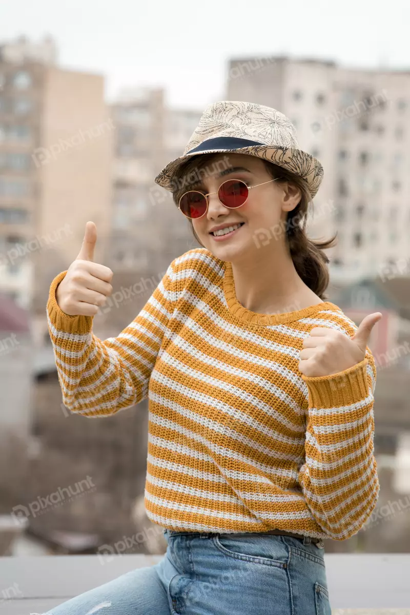 Free Premium Stock Photos young cute woman in a cap and glasses posing in outside and showing thumbs up . high quality photo