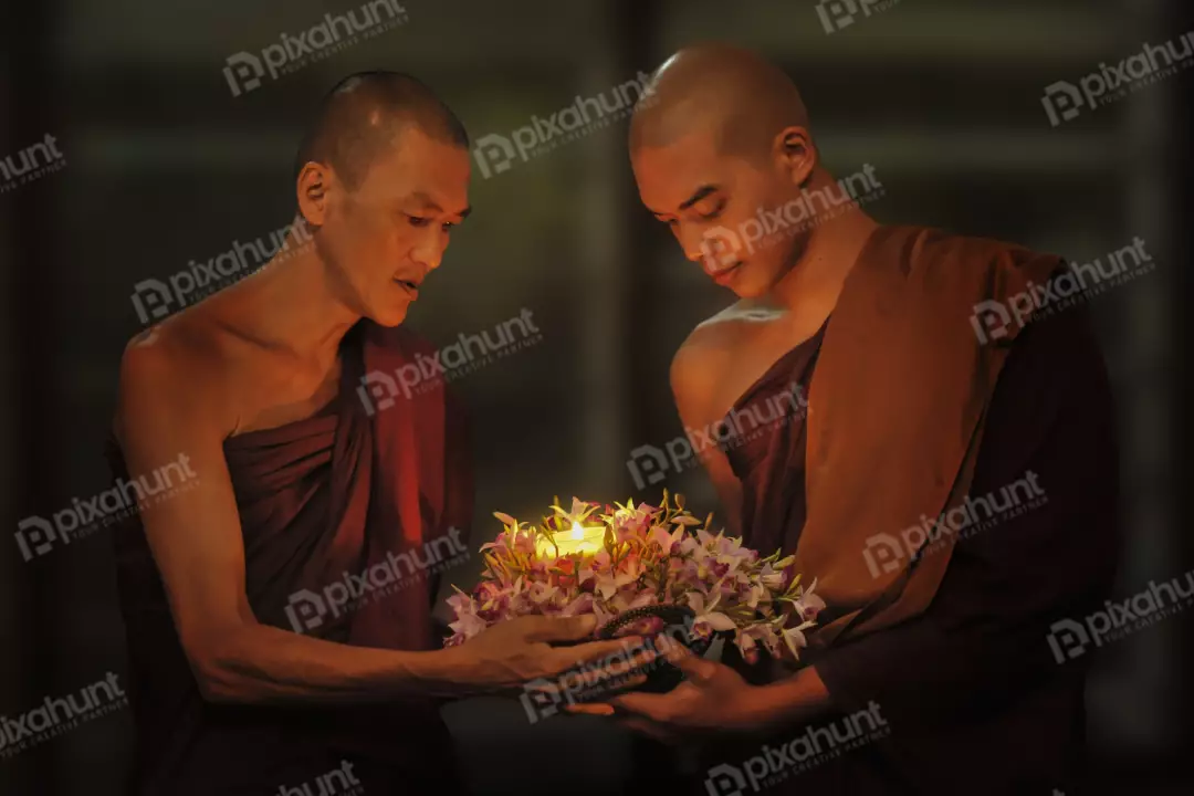 Free Premium Stock Photos Two Buddhist monks holding a candle and the older monk is holding a flower