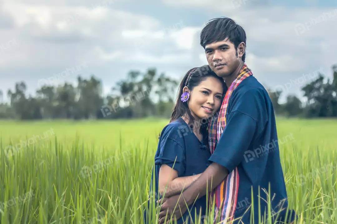 Free Premium Stock Photos A couple standing in a green field and man is wearing a blue shirt and the woman is wearing a traditional Thai dress