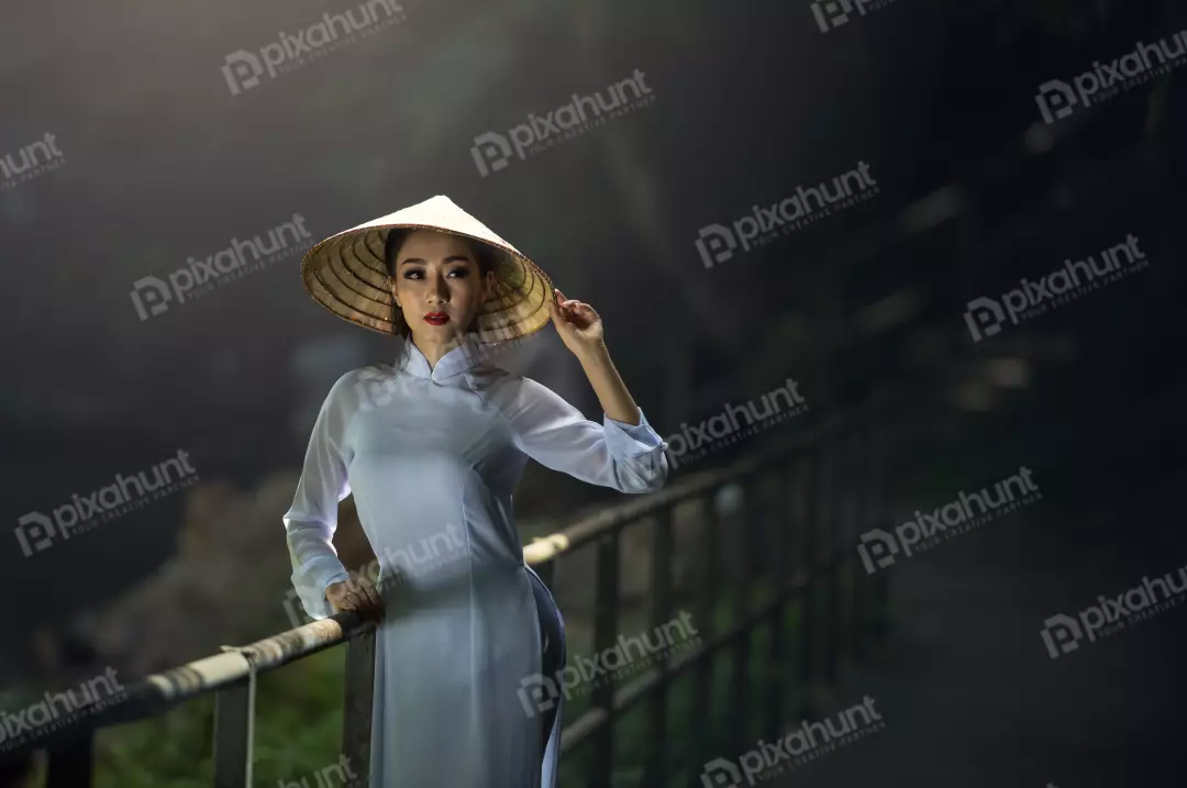 Free Premium Stock Photos Girl wearing a traditional Vietnamese conical hat with standing in a dark place with the light from a window falling on her face