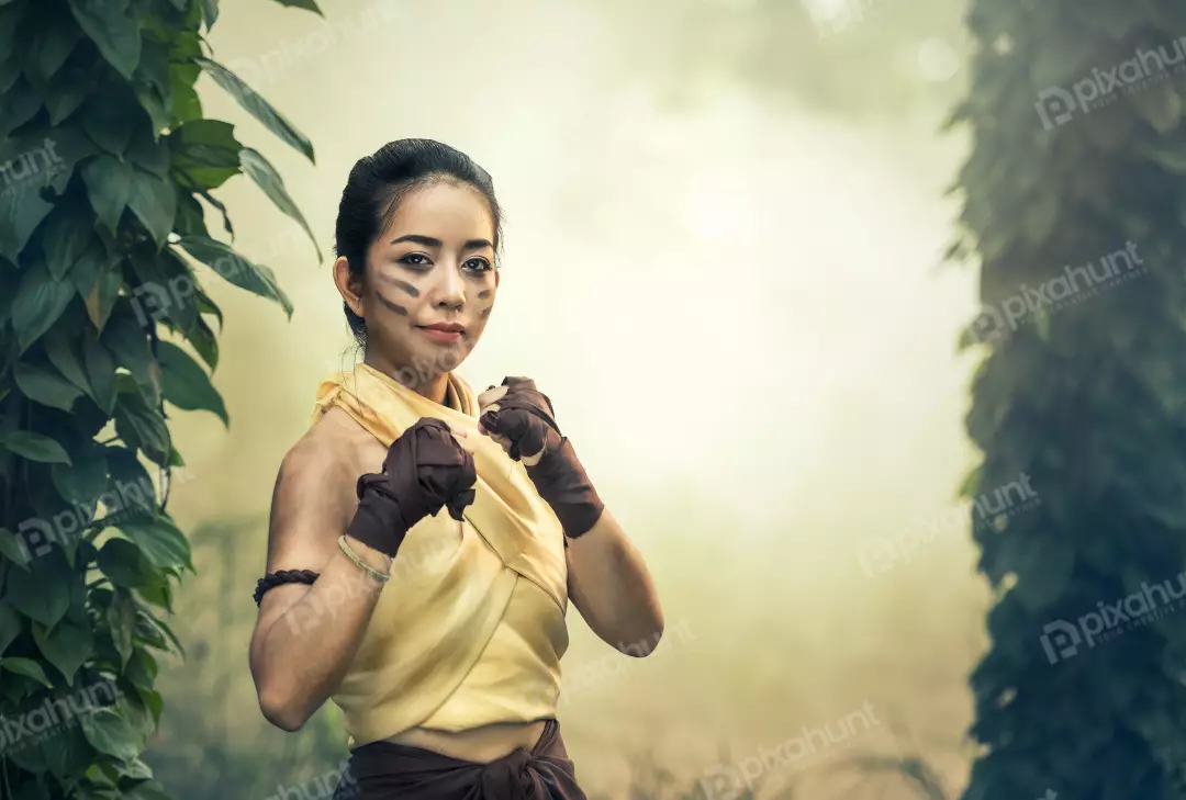 Free Premium Stock Photos A woman in a fighting stance and wearing a yellow tank top and brown shorts, and her hair is tied back in a bun