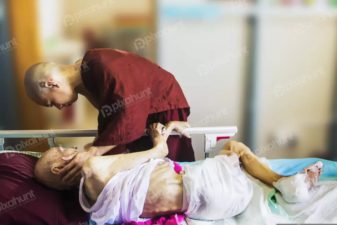 Free Premium Stock Photos A monk sitting next to a hospital bed, leaning over an elderly patient.