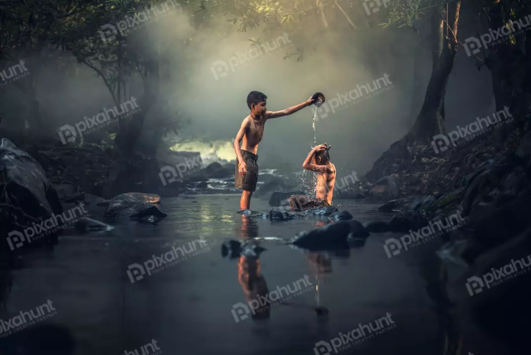 Free Premium Stock Photos Two boys who are bathing in a river and standing in the water and the one on the left is pouring water over the head of the boy on the right