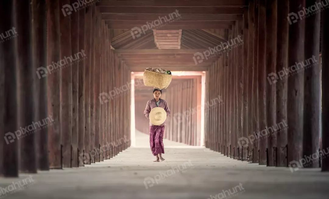 Free Premium Stock Photos A woman who is walking away from the camera and carrying a large basket on her head and is wearing a traditional Burmese longyi