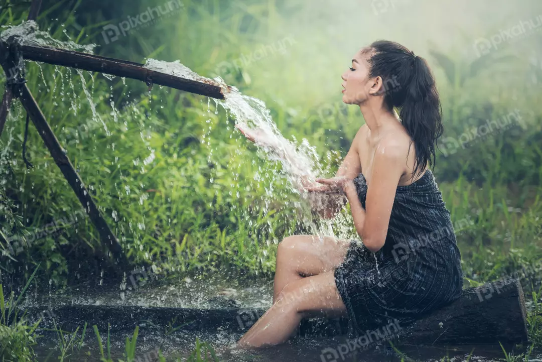 Free Premium Stock Photos A Girl bathing in a river and sitting on a rock with her long hair flowing down her back