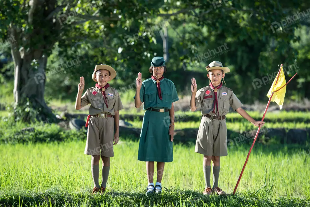 Free Premium Stock Photos Three scouts standing in a field, with the tallest in the middle and wearing green shirts and brown shorts