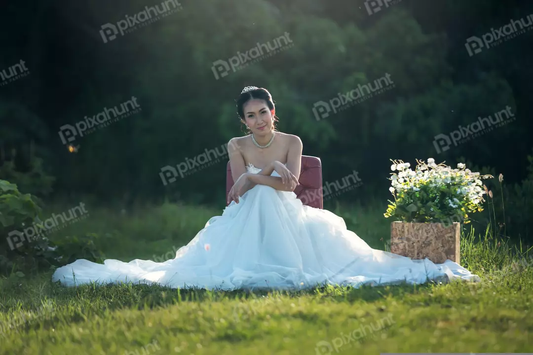 Free Premium Stock Photos The bride is sitting on a red chair in the middle of a field and wearing a white wedding dress and has her hair in a bun