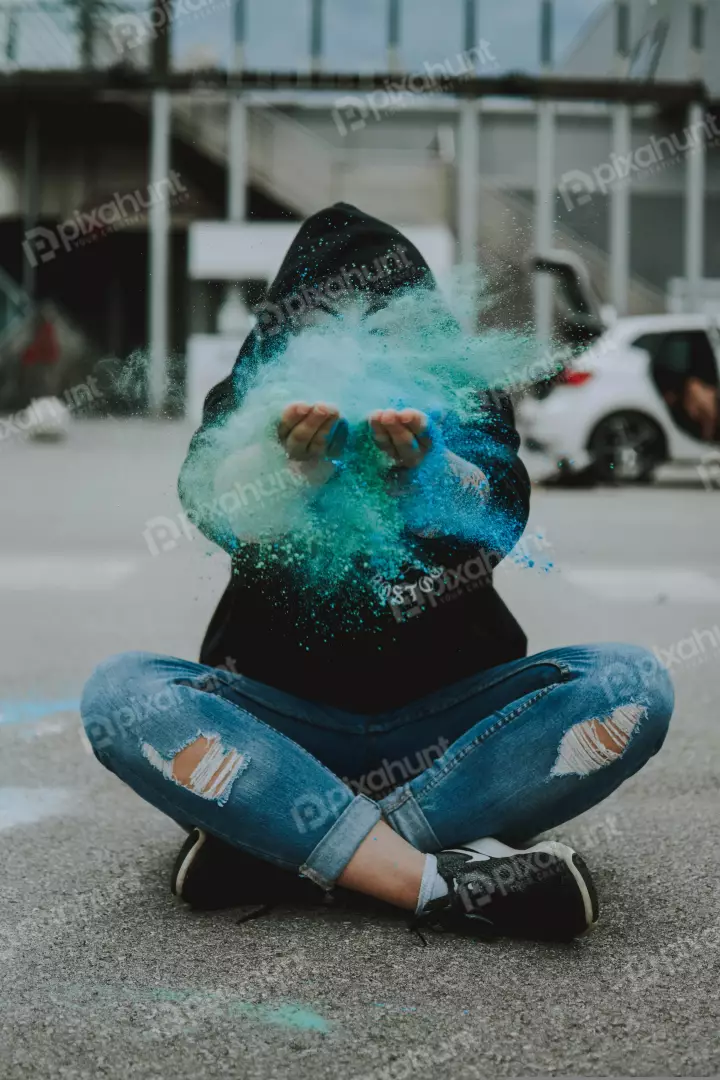 Free Premium Stock Photos a person sitting on the ground with a colorful powder in their hands