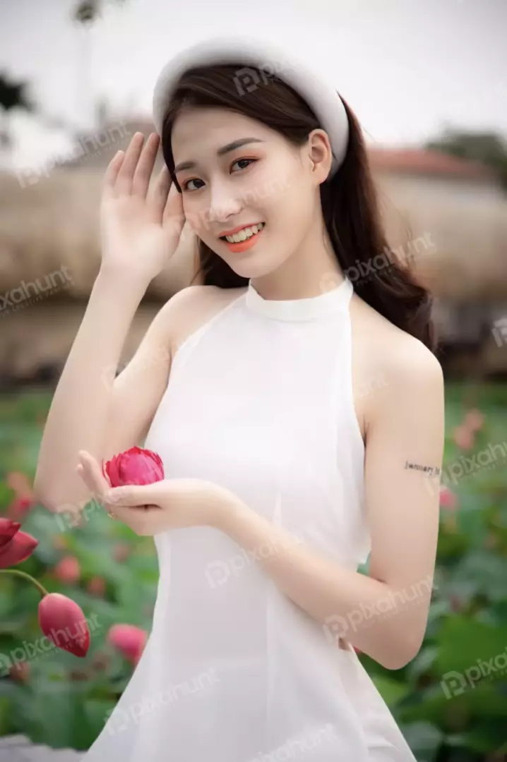 Free Premium Stock Photos A beautiful young woman in a white dress standing in a field of lotuses