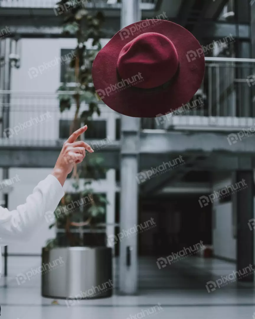 Free Premium Stock Photos A red hat is in the air and is being held up by a finger