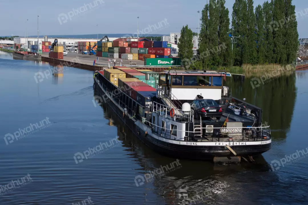 Free Premium Stock Photos A large ship in a river ship is carrying a variety of containers and there are trees and buildings