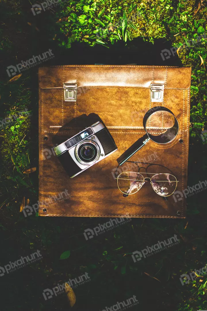 Free Premium Stock Photos A flat lay of a vintage camera, a magnifying glass, and a pair of glasses on a brown leather case