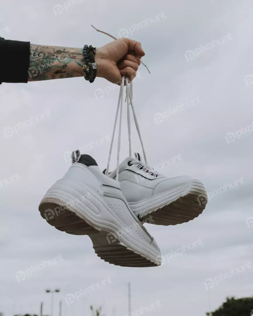 Free Premium Stock Photos A hand is holding a pair of white shoes by the laces