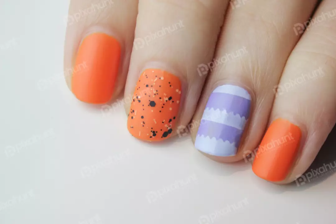 Free Premium Stock Photos A close-up of a hand with an orange and purple nail polish design