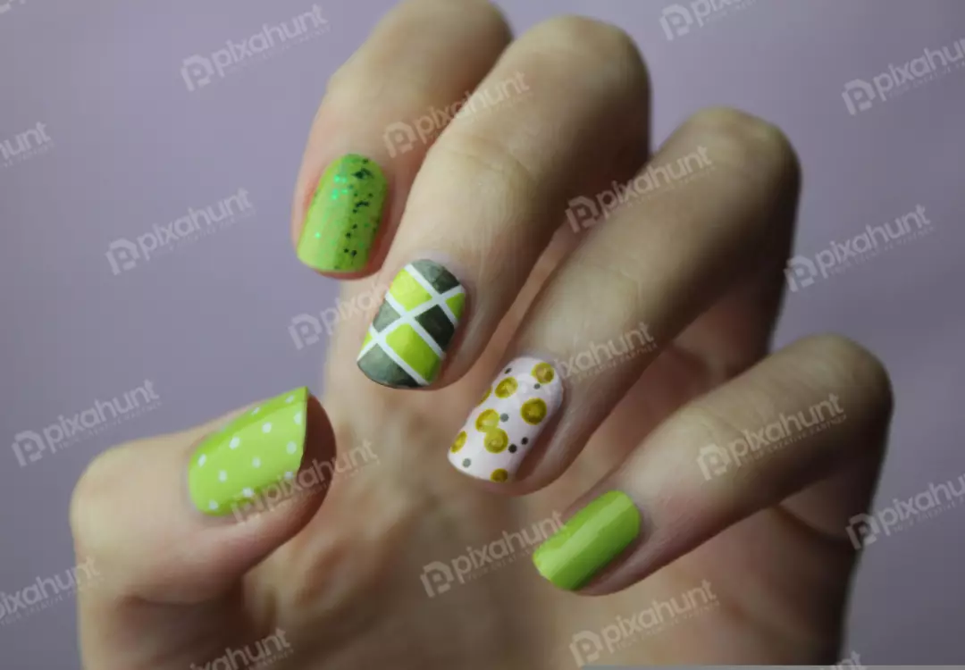 Free Premium Stock Photos A close-up of a hand with a green and yellow nail polish design