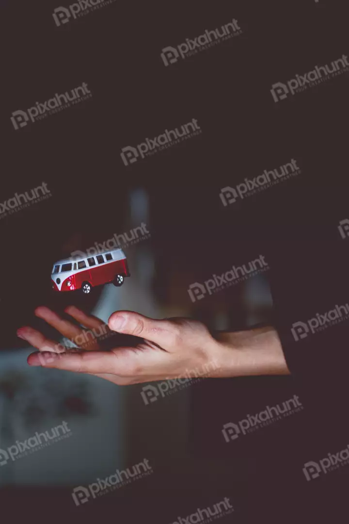 Free Premium Stock Photos a photograph of a red and white Volkswagen bus toy in the palm of a hand