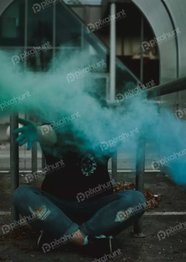 Free Premium Stock Photos A woman sits on the ground with her hand outstretched, and green smoke billows out from behind her