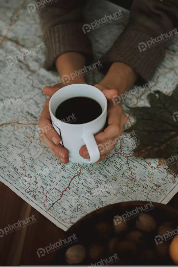 Free Premium Stock Photos Coffee cup is placed on a folded map and person is wearing a brown sweater