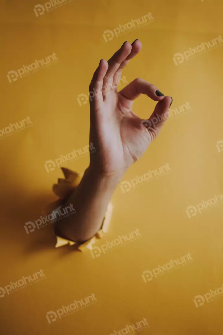 Free Premium Stock Photos a hand emerging from a hole in a yellow wall